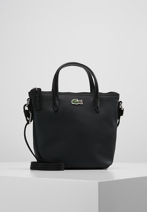 Petit sac à main noir texturé avec deux poignées, une bandoulière amovible et un logo crocodile vert au centre devant.