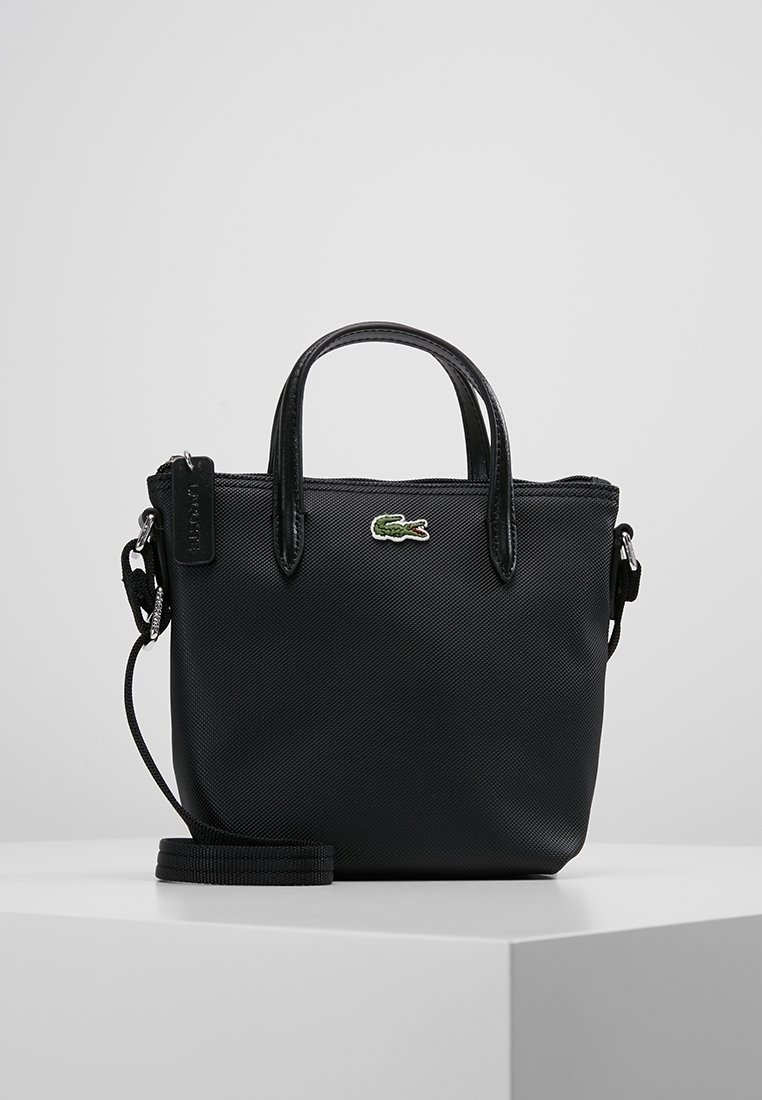 Petit sac à main noir texturé avec deux poignées, une bandoulière amovible et un logo crocodile vert au centre devant.