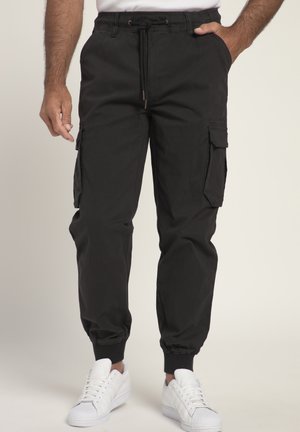 Black cargo pants with five pockets, an elastic waistband, and ankle cuffs. Paired with white sneakers, featuring a classic design.