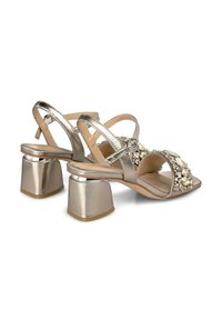 Metallisch goldene Sandalen mit Blockabsätzen, verziert mit dekorativen Steinen an den Riemen. Offene Zehen und verstellbare Knöchelriemen.