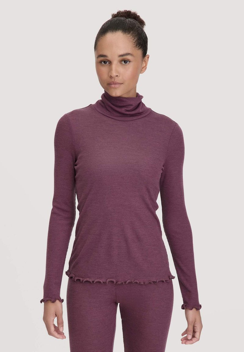 Langsleeve turtleneck top in donkerplum ribbelstof met golfvormige zoom en mouwranden, gedragen met bijpassende onderkleding, wat een samenhangende look creëert.