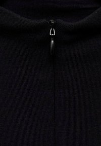 Black, ribbed fabric with a half-zip closure. The zipper pull is smooth and rounded, blending with the fabric's color and texture.
