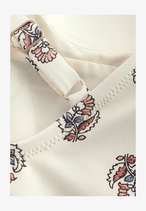 Floral-patterned fabric in cream with accents of blue and red. Features a gold hardware adjustable strap and textured stitching detail.