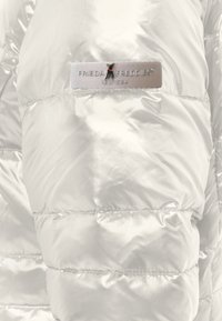 Metalen zilverkleurig pufferjack met doorgestikte delen en een zijdezachte textuur. Heeft een grijs label met de merknaam "FRIEDA FREDDIE NEW YORK".