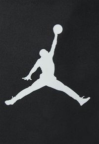 Fundo texturizado preto apresentando uma grande silhueta branca de uma figura a saltar, alcançando uma bola de basquete com membros estendidos.