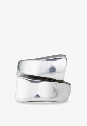 Anillo de tono plateado pulido con un diseño orgánico y retorcido; presenta superficies suaves y texturizadas, creando contraste visual y profundidad.