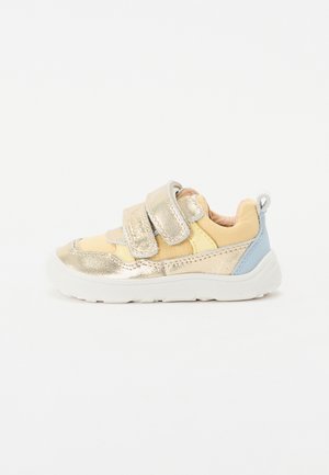 Sneaker con velcro con tomaia in tessuto metallico dorato e giallo morbido, accentuazione blu sul tallone, interno imbottito e suola in gomma bianca.