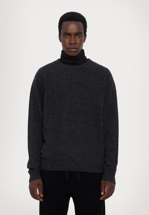 Dark gray sweater with a high turtleneck, ribbed cuffs, and hem. Soft texture, relaxed fit, minimal design, worn over a black base layer.