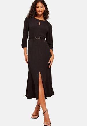 Zwarte midi-jurk met een sleutelgat-halslijn, driekwartmouwen, een ceintuur in de taille en een split aan de voorkant. Glad stof met minimale textuur.