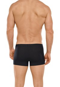 Costume da bagno da uomo a righe nere, realizzato in tessuto leggero. Presenta un design aderente e una vita elasticizzata. Tessuto liscio, taglio a vita media.