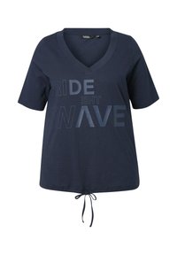 Camiseta de algodón azul marino con escote en V, mangas cortas y un cordón en el dobladillo. Texto impreso "SURFEA LA OLA" en tonos más claros.