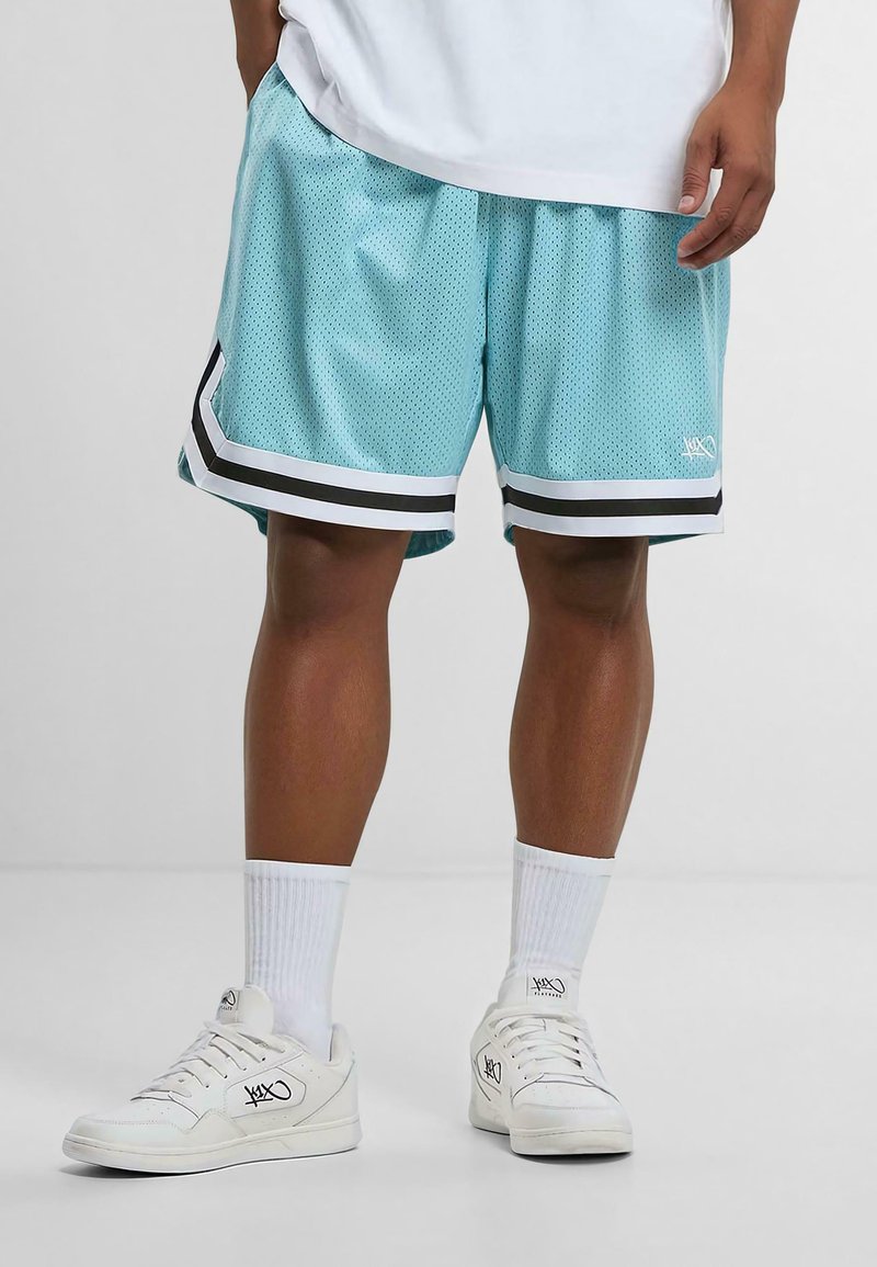 Shorts de basket en maille bleu clair avec des accents noirs et blancs, dotés de bandes latérales et d'une taille élastique, associés à des baskets blanches.