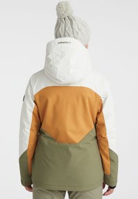 Color-blocked jacket featuring white, brown, and olive green sections. Equipped with a hood and textured fabric. Pom-pom hat complements design.