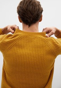 Golden yellow knit sweater with a textured, waffle pattern. Features a ribbed crew neckline and raglan sleeves.