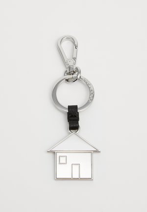 Stříbrný klíčenka v podobě domu s černým koženým akcentem. Dům obsahuje výkroje pro dveře a okna, připevněn na kulatém kovovém kroužku.