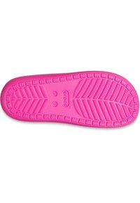 La suola dei Crocs rosa presenta una superficie testurizzata e decorata con scanalature per una migliore aderenza, materiale morbido e il marchio "CROCS" al centro.