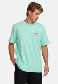 Turquoise short-sleeve t-shirt made of soft cotton, featuring a small black Billabong logo on the left chest and a relaxed fit.