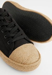 Mustad mustadest kangast kingad, millel on jute köistekork, kummist tallad, millel on tekstuuritud muster, ja lapikud paelad.