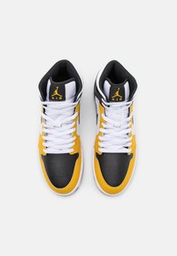 Tenisky s vysokým střihem, které mají černou koženou špičku, žlutou koženou střední část a bílé tkaničky. Černá síťovina uvnitř a detaily loga.