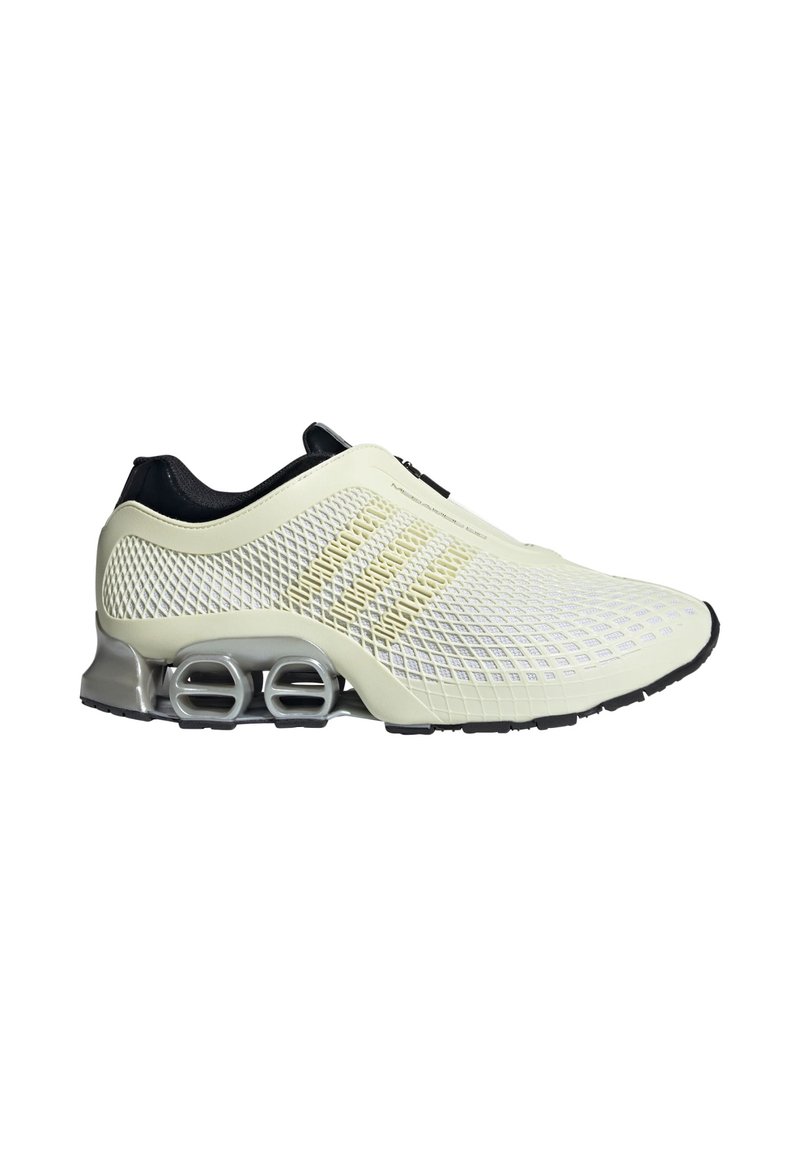 Lyse creme sneakers med en mesh-overdel, sorte accenter og en gummisål, der har synlige luftdæmpningselementer og et tekstureret design.