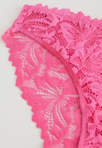 Perizoma in pizzo rosa con motivi floreali, bordi ondulati e finiture in satin morbido. La texture è delicata e intricata.