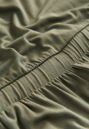 Olive green fabric with a smooth texture featuring gathered elastic sections, showing soft wrinkles and folds for added dimension.