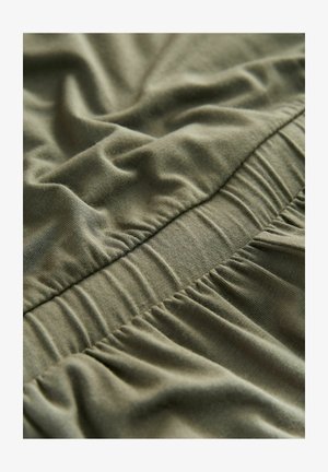 Olive green fabric with a smooth texture featuring gathered elastic sections, showing soft wrinkles and folds for added dimension.