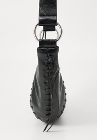 Schwarze Lederhandtasche mit runder Form, sichtbaren Nähten an der Seite und einem silbernen Ring, der an einem Riemen befestigt ist.