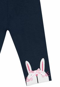 Leggings de algodón en color azul marino con un gráfico de un conejito blanco en el tobillo, con detalles en rosa que incluyen las orejas y un lazo, además de bigotes negros.