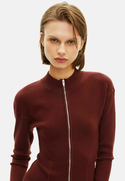 Maglione borgogna con zip, colletto a coste e maniche aderenti, caratterizzato da una texture liscia e una silhouette sagomata che esalta la forma del corpo.