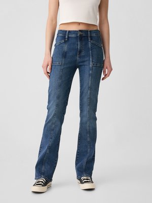 Light blue denim flared jeans with visible stitching details and front pockets, paired with black and white canvas sneakers.