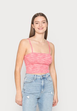 Top cropped justo, canelado, em um padrão mesclado de rosa e branco. Apresenta alças finas ajustáveis e um decote quadrado. Usado com jeans claros desgastados.