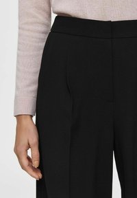 Zwarte broek met een aangesloten ontwerp, voorzien van plooien, een gladde textuur en een hoge tailleband, gecombineerd met een lichtroze trui-sleef.