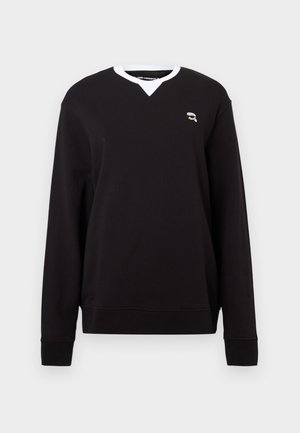 Sudadera negra de manga larga, con escote en V, cuello blanco y pequeño logo bordado en el pecho. Tejido suave con una textura lisa.