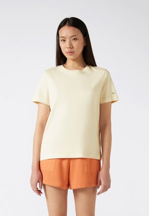 Losse gele katoenen t-shirt met korte mouwen en een ronde halslijn, voorzien van een geborduurd logo op de borst en logo-detail op de mouw.
