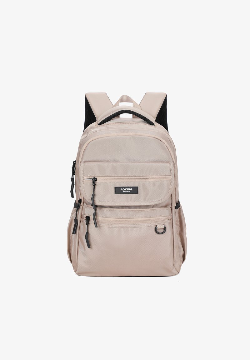 Zaino in tessuto beige con due tasche frontali con zip, spallacci imbottiti e una maniglia superiore. Presenta dettagli neri e un'etichetta con logo.