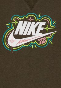 Brown sweatshirt featuring a large, colorful Nike logo with a pink swoosh and vibrant accents in green and blue, on a textured fabric.