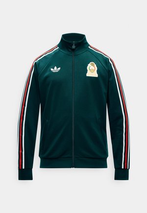 Dunkelgrüne Trainingsjacke mit Reißverschluss, mit roten, weißen und schwarzen Streifen an den Ärmeln, Adidas-Logo auf der linken Brust und gesticktem Emblem auf der rechten Brust.