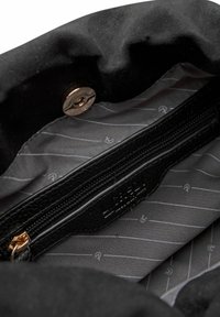 Schwarze Stoff-Schultertasche mit einem Innenraum, der eine Reißverschlusstasche aus strukturiertem Leder aufweist, mit einem grauen Futtermuster und subtilen Branding-Details.