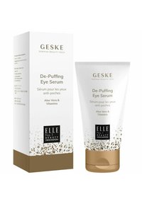 Siero occhi De-Puffing in un tubo squeezable bianco e oro con testo nero. La scatola presenta un design simile, evidenziando Aloe Vera e vitamine.