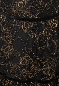 Black lace fabric with gold floral patterns, featuring a layered design and a textured, sheer appearance. Velvet accents are visible.