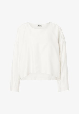Blusa blanca de manga larga para mujer con escote redondo, dobladillo ligeramente crop, y tela suave, con etiqueta "Drykorn" en el interior del cuello.