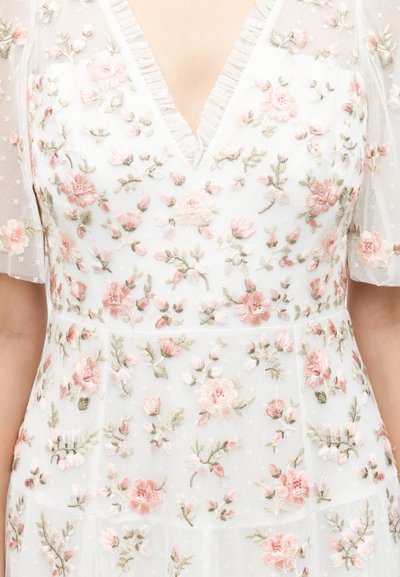 Λευκό φόρεμα με διάφανα κοντά μανίκια, διακοσμημένο με λεπτή ροζ και πράσινη κεντητή λουλουδάτη διακόσμηση και V-λαιμόκοψη.