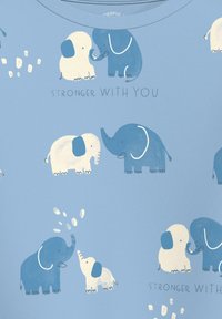 Jasnoniebieska tkanina z zabawnymi ilustracjami słoni w białym i niebieskim. Napis brzmi "MOCNIEJSI Z TOBĄ". Wzór zawiera różne pozy słoni.