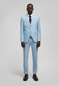 Lichtblauw pak met een slim fit, enkel-breasted blazer, notch revers en bijpassende broeken. Een wit overhemd en een marineblauwe das maken de look compleet.