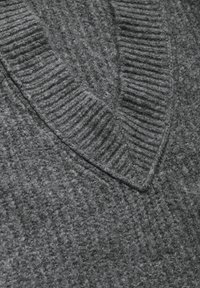 Pull en tricot gris foncé avec un design en V côtelé. Tissu doux et texturé présentant un mélange de motifs lisses et duveteux.