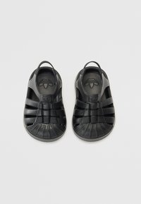 Sandali neri in gomma con tomaia texturizzata, design aperto e molteplici cinturini. Punta rinforzata con un delicato dettaglio del logo all'interno.