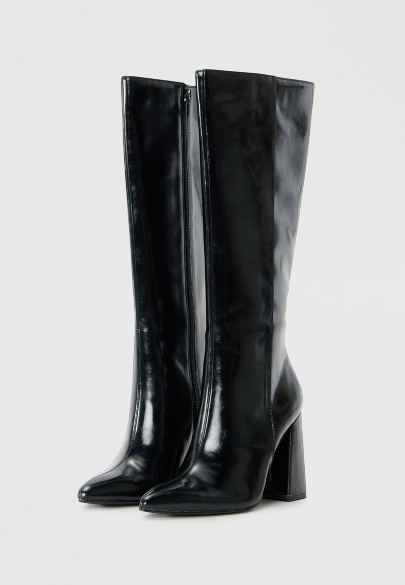 Stivali neri al ginocchio realizzati in pelle sintetica lucida. Presentano una punta a forma appuntita e un tacco spesso, con una cerniera laterale per la chiusura.