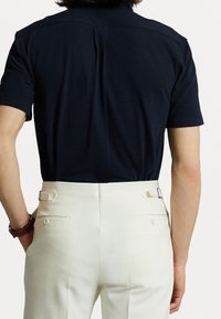 Marinblå kortärmad skjorta i kombination med krämfärgade byxor med slät textur, sidjusterare och bakfickor.