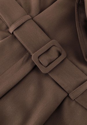 Bruine stoffen riem met bijpassende rechthoekige gesp op een bruin kledingstuk met textuur, met zichtbare naaddetails en stiksels.